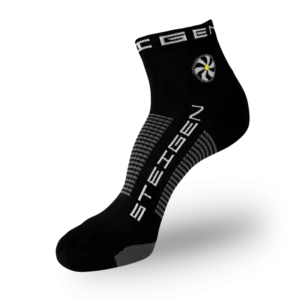 A black Steigen athletic sock featuring a circular white and yellow flower graphic on the ankle. The brand name is printed vertically in white on the foot, with grey and black horizontal stripes wrapping around the arch.