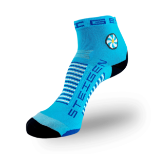 A Steigen brand quarter-length athletic sock on a transparent background. The sock is bright blue with a black toe and heel. It features a circular white and yellow flower-like graphic on the ankle. "STEIGEN" is printed vertically in navy blue on the top of the foot, with white and navy horizontal stripes across the arch.