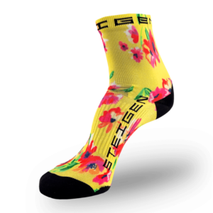 A bright yellow athletic sock covered in a vibrant pink, red, and blue floral pattern. It features a black toe and heel with the word "STEIGEN" printed vertically in black along the side of the foot.