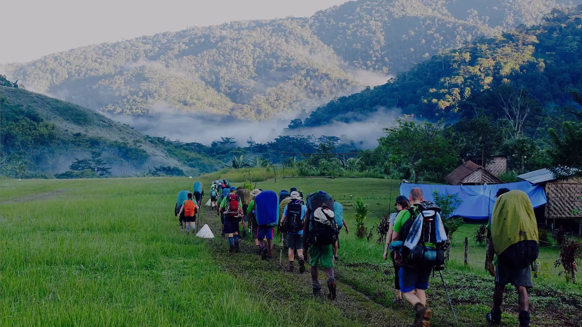 Several images show large groups of trekkers and local guides posing in high-altitude meadows or trekking through misty valleys along the Kokoda Track.