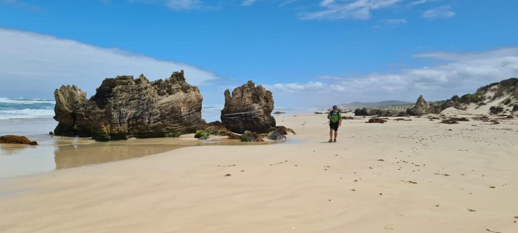 Man trekking the Aussie Camino, walking alone on beautiful beach.